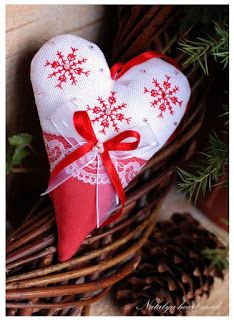 a heart shaped ornament sitting on top of a basket next to pine cones