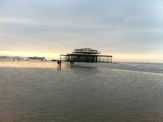 people walking on the beach next to an old structure