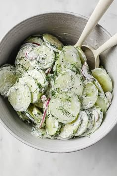 a white bowl filled with cucumbers and dill