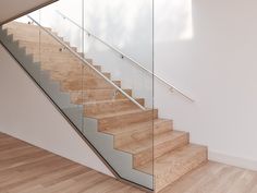 a wooden and glass stair case in a white room with wood flooring on the side