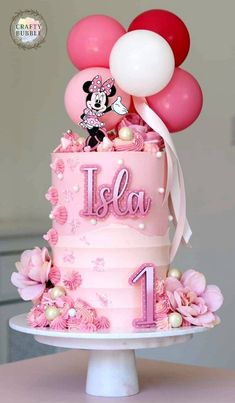 a minnie mouse cake with balloons and the number one on it for a first birthday