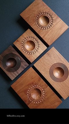 four wooden coasters with designs on them sitting next to each other in front of a black background