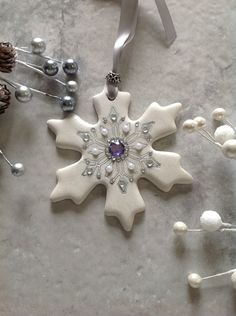 a snowflake ornament is hanging from a silver ribbon on a table