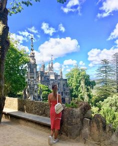 a woman in a red dress is looking at the castle