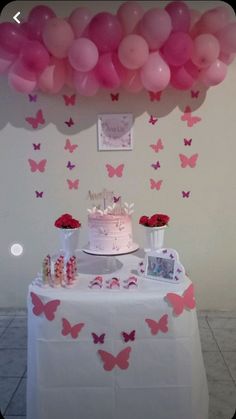 a table topped with a cake and lots of pink butterflies on it's wall