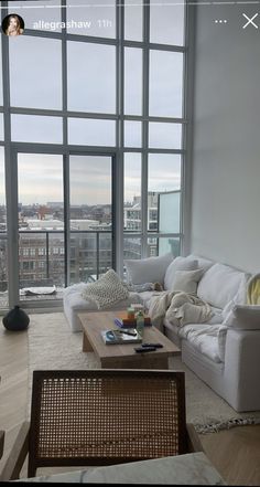 a living room filled with furniture and large windows overlooking the cityscape in the distance