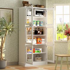 a white book shelf filled with lots of items next to a potted plant and window