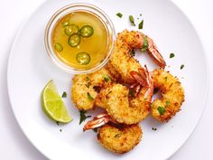 a white plate topped with fried shrimp next to a bowl of sauce and a lime wedge