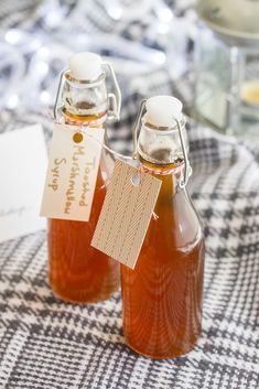 two bottles of honey sitting on top of a checkered table cloth with tags attached to them