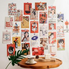 a wooden table topped with a cup filled with coffee next to a wall covered in posters