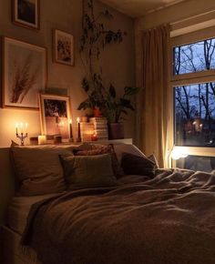 a bed sitting next to a window with candles on top of it in front of a window