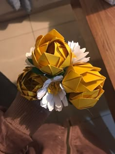 a bouquet of yellow and white flowers sitting on top of a wooden table