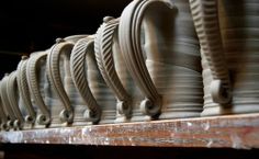 rows of pottery sitting on top of a wooden shelf