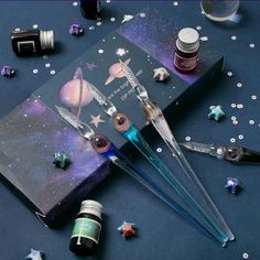 an assortment of crafting supplies including pens, glues and star shaped objects on a blue surface