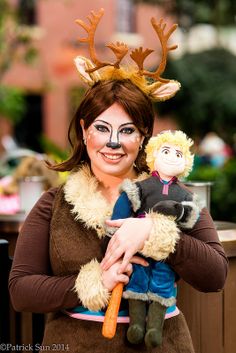 a woman in costume holding a stuffed animal and wearing antlers on it's head