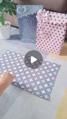 someone is wrapping presents on the floor with pink and blue polka dot paper, while another person holds up a video game controller