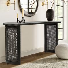 a console table with two candles on it in front of a mirror and vases