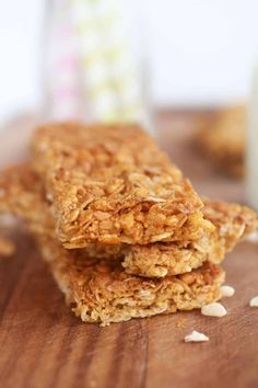 three granola bars sitting on top of a wooden table next to a glass of milk