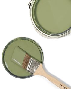 two green paint cans one with a wooden handle and the other has a brush in it