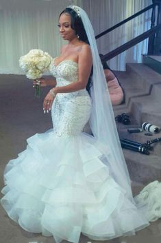 a woman in a wedding dress holding a bouquet and posing for a photo on her phone