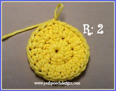 a crocheted yellow round ornament is shown with the word r 2 below it