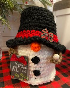 a crocheted snowman with a happy holidays sign on it's chest