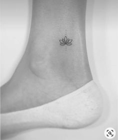 a small lotus flower tattoo on the side of a foot, with an arrow in the middle