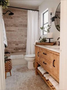 a white toilet sitting next to a wooden sink vanity in a bathroom under a window