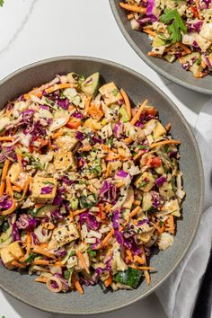 a white bowl filled with salad on top of a gray table cloth next to a wooden spoon