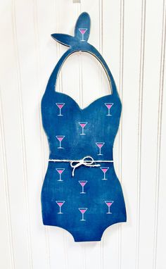 a blue bathing suit with martini glasses on it hanging from a hook in front of a white wall