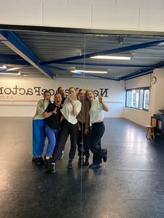 five people posing for a photo in an empty room with a sign that says news office factory