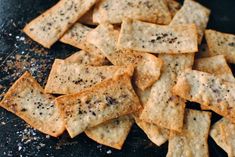 some crackers are sitting on a black plate with seasoning sprinkles