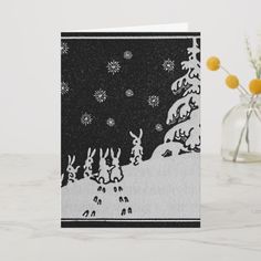 a black and white christmas card with reindeers in the snow, surrounded by yellow flowers