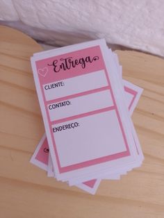 three pink and white tags on top of a wooden table