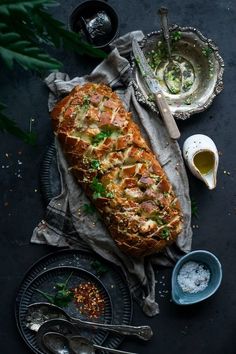 a loaf of bread sitting on top of a table next to bowls and spoons