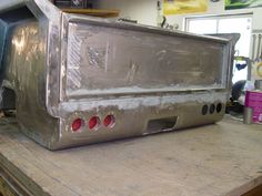 an old metal microwave sitting on top of a wooden table in a room with other appliances