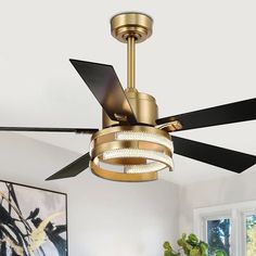 a gold ceiling fan with black blades in a white room