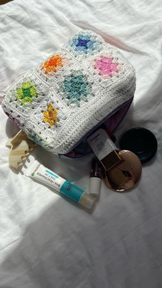 an open purse sitting on top of a bed next to makeup and eye shadow brushes