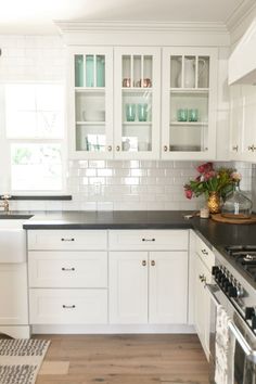 a kitchen with white cabinets and black counter tops