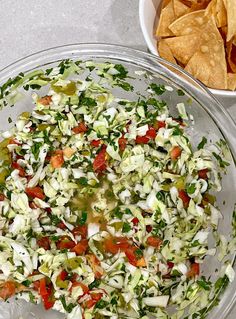 a glass bowl filled with chopped vegetables next to a bowl of tortilla chips