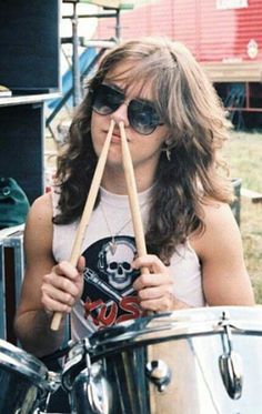 a woman with sunglasses on holding drums in front of her face