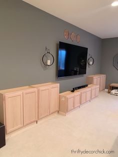 a living room with gray walls and white carpeted flooring, tv mounted on the wall