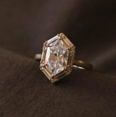 an old - fashioned diamond ring sits on a brown cloth in front of a black background