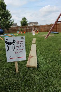 a sign that is sitting in the grass next to a swing set and some kind of slide