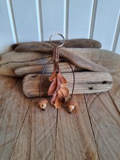 a pair of earrings with acorns hanging from them on a piece of wood