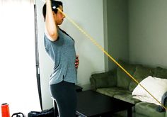 a pregnant woman holding a pair of scissors in her hand while standing next to a couch