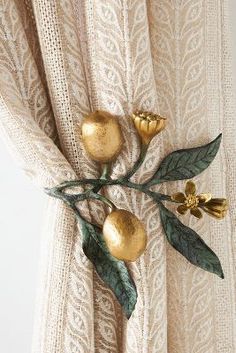 the curtain is decorated with gold flowers and green leaves on it's rod ends