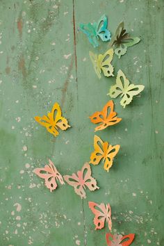 colorful butterflies are arranged on a green surface with peeling paint and chipped edges,