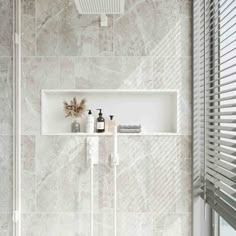 a white tiled bathroom with shelves and towels on the shelf next to the bathtub