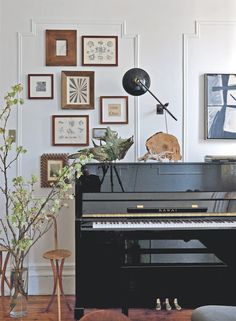 a living room with a black piano and pictures on the wall